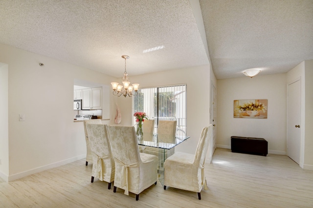 dining room with a textured ceiling, light wood-type flooring, and a notable chandelier