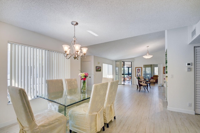 dining area with a notable chandelier, vaulted ceiling, a textured ceiling, and light hardwood / wood-style flooring