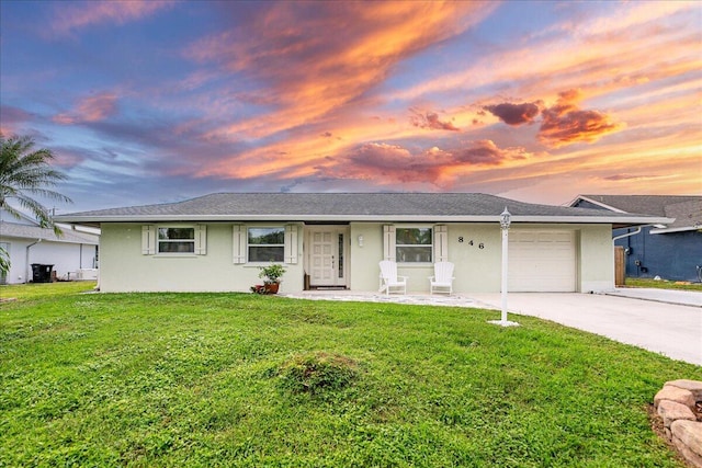 ranch-style home featuring a garage and a lawn