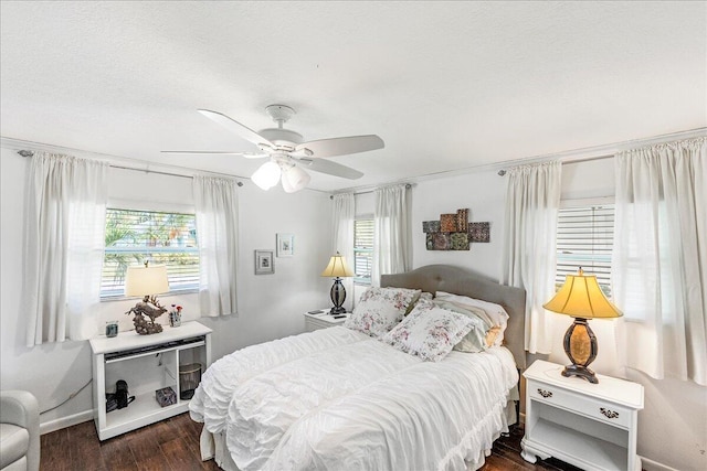 bedroom featuring a textured ceiling, dark hardwood / wood-style flooring, multiple windows, and ceiling fan