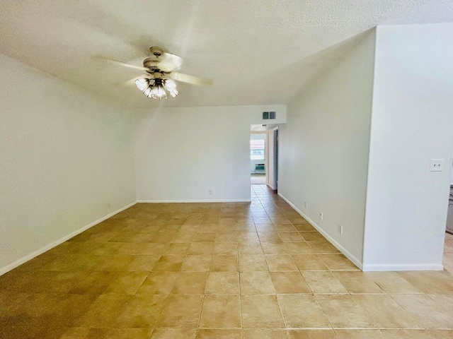 tiled empty room featuring ceiling fan, lofted ceiling, and a textured ceiling