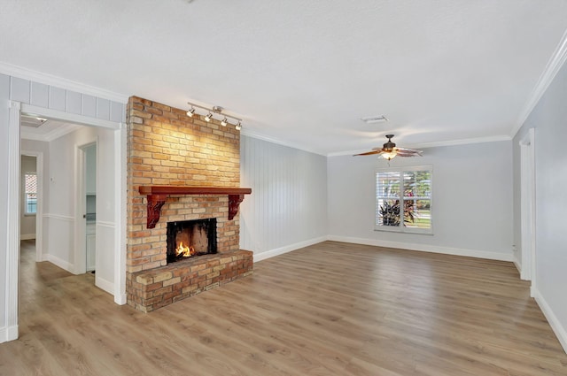 unfurnished living room featuring ceiling fan, crown molding, a fireplace, and light hardwood / wood-style flooring