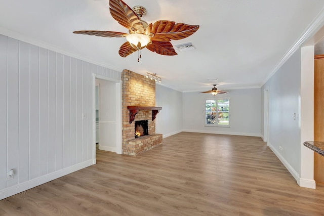 unfurnished living room featuring a fireplace, wooden walls, light hardwood / wood-style floors, and ornamental molding