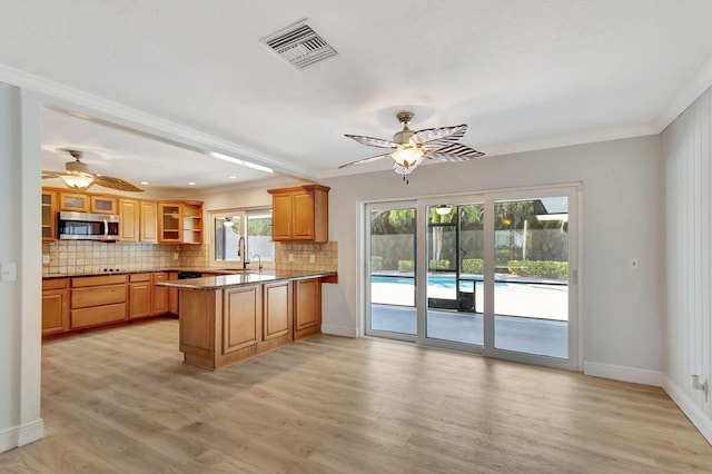 kitchen with ceiling fan, sink, kitchen peninsula, crown molding, and light hardwood / wood-style floors