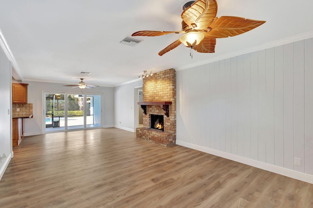 unfurnished living room featuring hardwood / wood-style floors, ornamental molding, wooden walls, and a brick fireplace