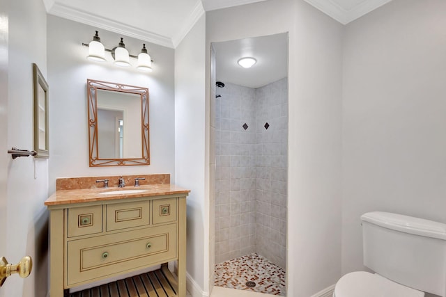 bathroom with toilet, a tile shower, crown molding, and vanity