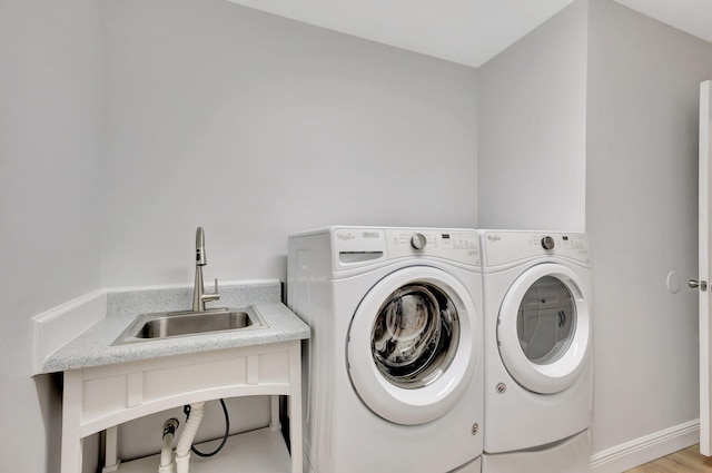 laundry room with washer and dryer, light wood-type flooring, and sink