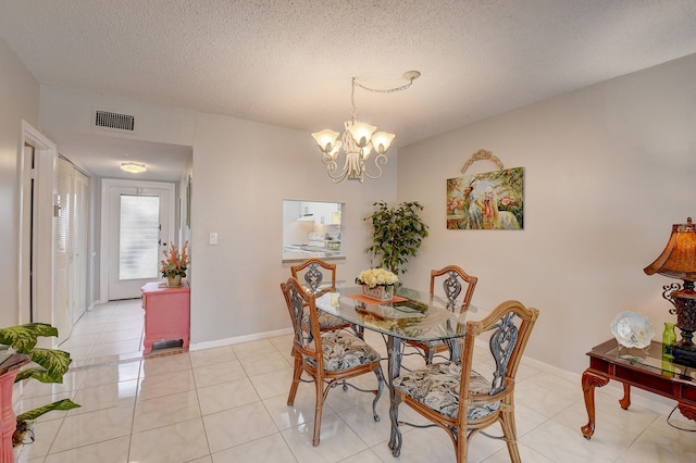 tiled dining area featuring a textured ceiling and an inviting chandelier