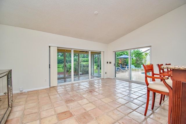 tiled empty room with high vaulted ceiling and a textured ceiling