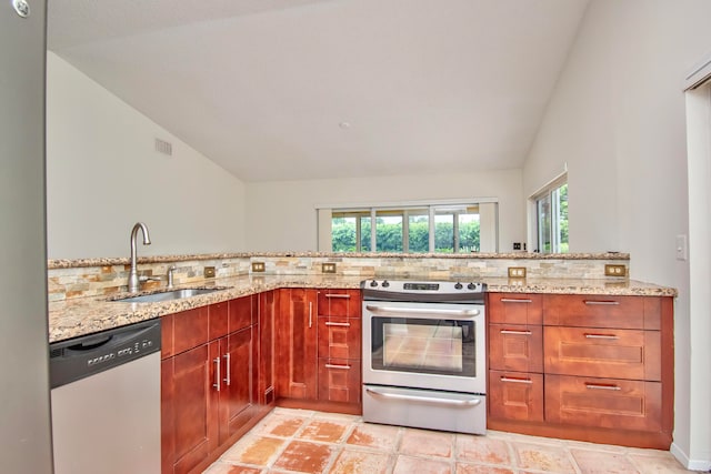 kitchen with lofted ceiling, sink, light stone countertops, kitchen peninsula, and stainless steel appliances