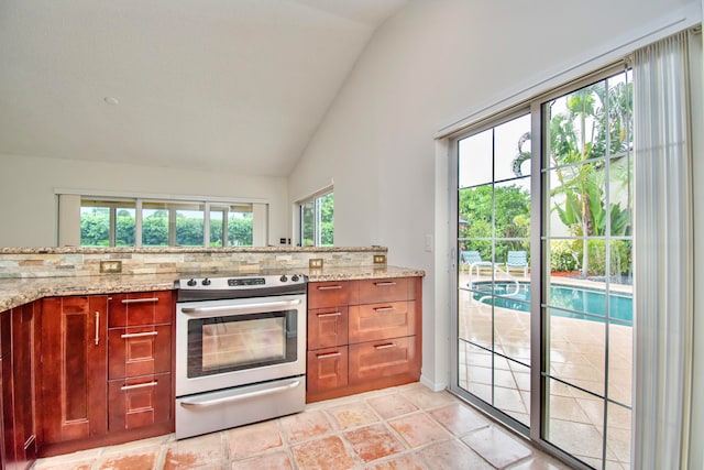 kitchen with vaulted ceiling, light stone countertops, and stainless steel range with electric stovetop