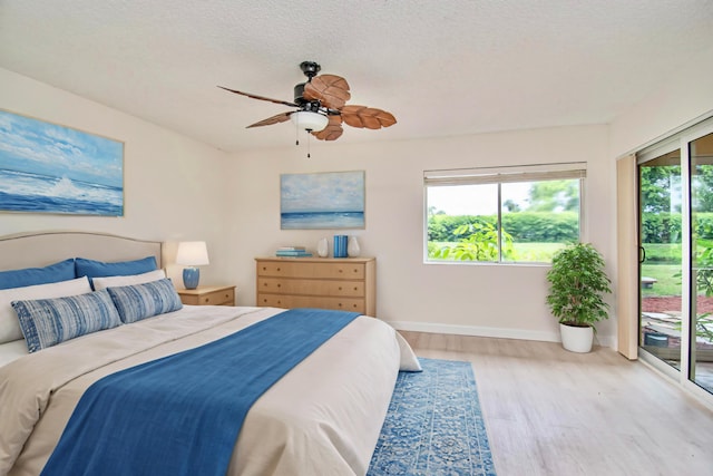 bedroom featuring ceiling fan, access to exterior, a textured ceiling, and light hardwood / wood-style flooring