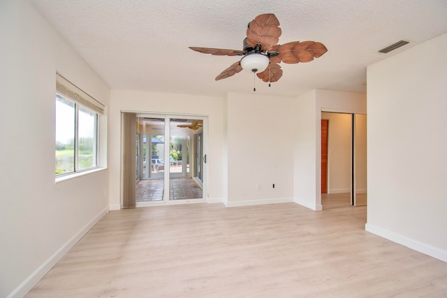 empty room featuring a textured ceiling, light hardwood / wood-style flooring, and ceiling fan