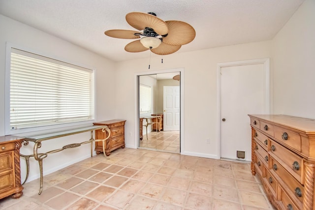 sitting room featuring ceiling fan, light tile patterned flooring, and a textured ceiling