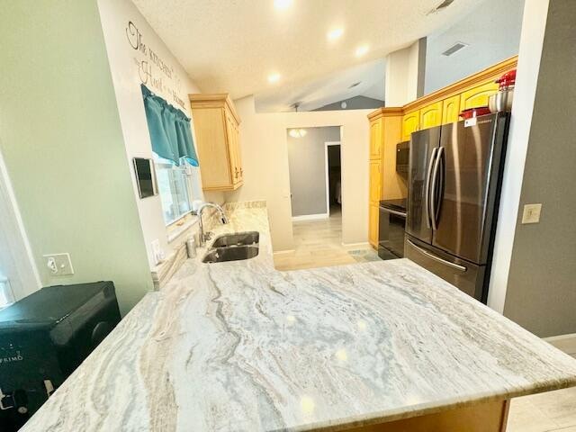 kitchen featuring sink, kitchen peninsula, lofted ceiling, light brown cabinetry, and black appliances