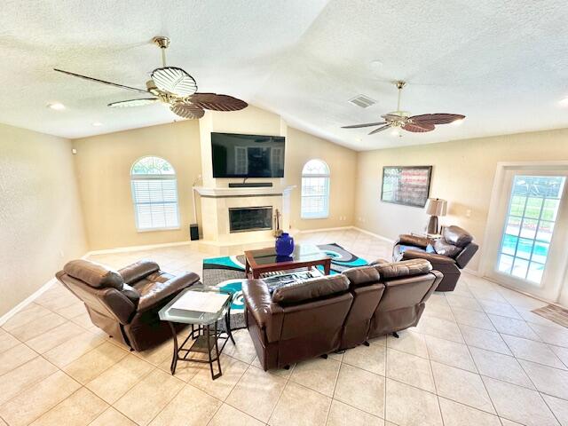 tiled living room featuring a textured ceiling, vaulted ceiling, and ceiling fan