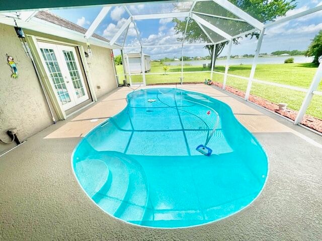 view of swimming pool with a patio area, a lanai, a yard, and french doors