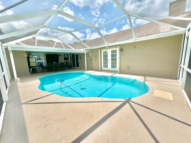 view of swimming pool featuring french doors, a patio, and glass enclosure