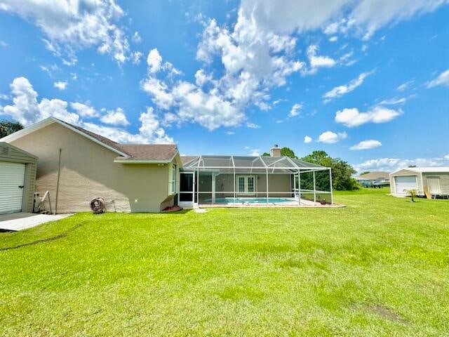 rear view of house with a lanai and a lawn