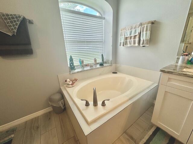 bathroom with vanity, wood-type flooring, and a tub to relax in