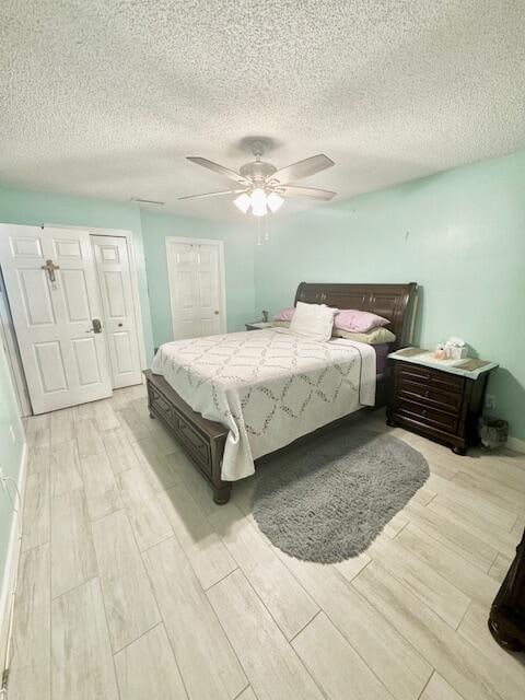 bedroom featuring ceiling fan, light hardwood / wood-style floors, and a textured ceiling