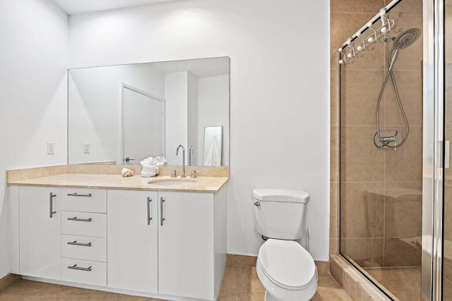 bathroom featuring tile patterned flooring, vanity, toilet, and walk in shower