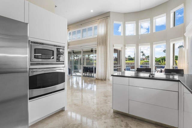 kitchen featuring white cabinets, stainless steel appliances, and a high ceiling