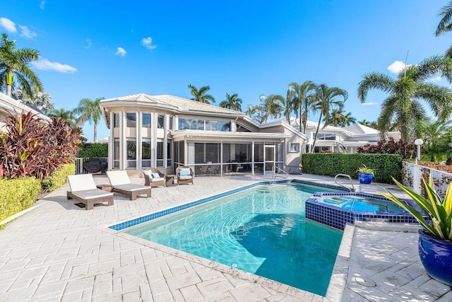 back of property with a swimming pool with hot tub, a patio, and a sunroom