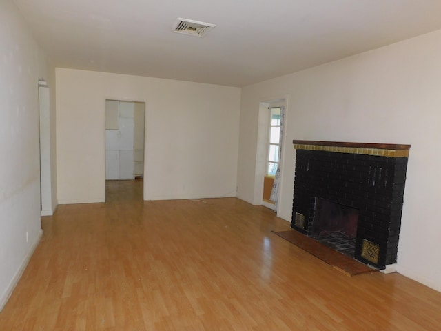 unfurnished living room featuring light hardwood / wood-style floors and a brick fireplace