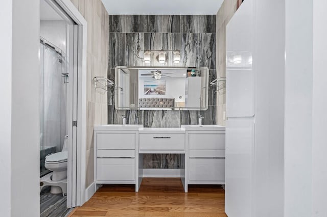 bathroom with hardwood / wood-style floors, vanity, toilet, and an enclosed shower