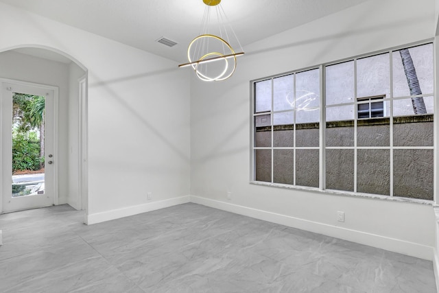 empty room featuring a chandelier and vaulted ceiling