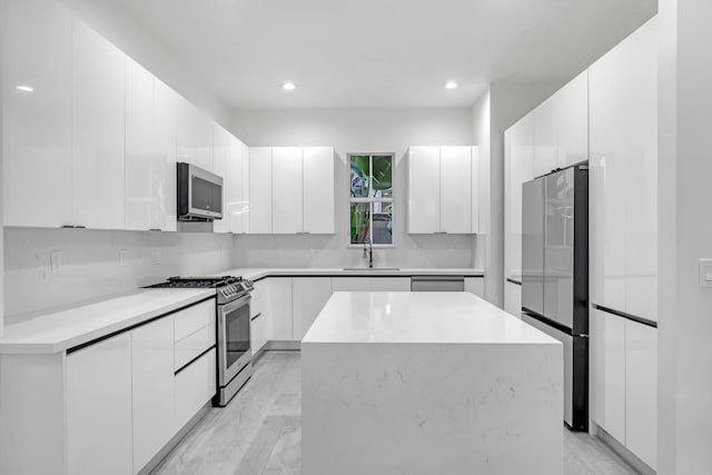 kitchen featuring a center island, white cabinets, sink, decorative backsplash, and appliances with stainless steel finishes