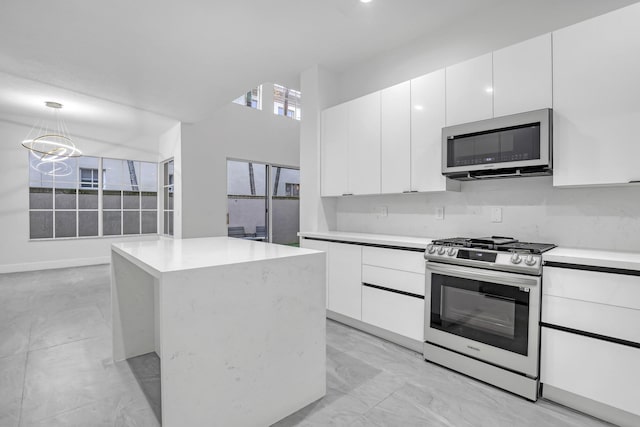 kitchen featuring appliances with stainless steel finishes, a center island, decorative light fixtures, and white cabinetry