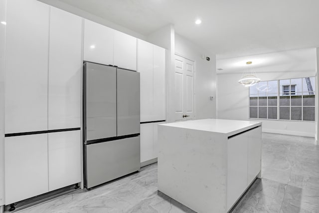 kitchen featuring stainless steel refrigerator, white cabinetry, a center island, and hanging light fixtures