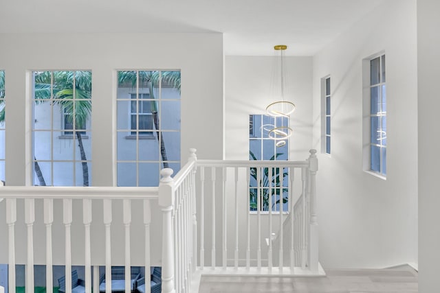 stairway featuring wood-type flooring and a notable chandelier