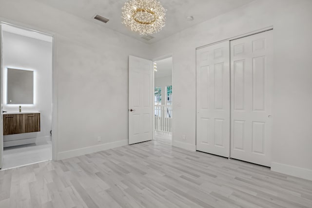 unfurnished bedroom featuring light wood-type flooring and a chandelier