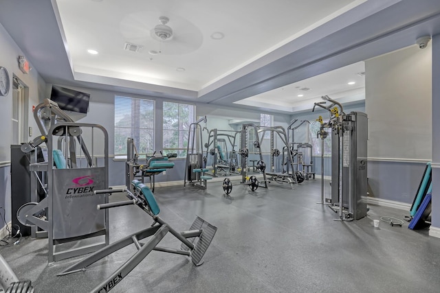 workout area featuring a tray ceiling and ceiling fan