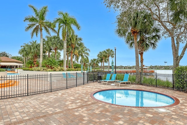 view of swimming pool featuring a water view and a patio area