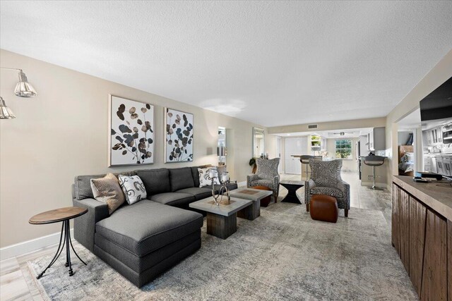 living area featuring baseboards, visible vents, and a textured ceiling