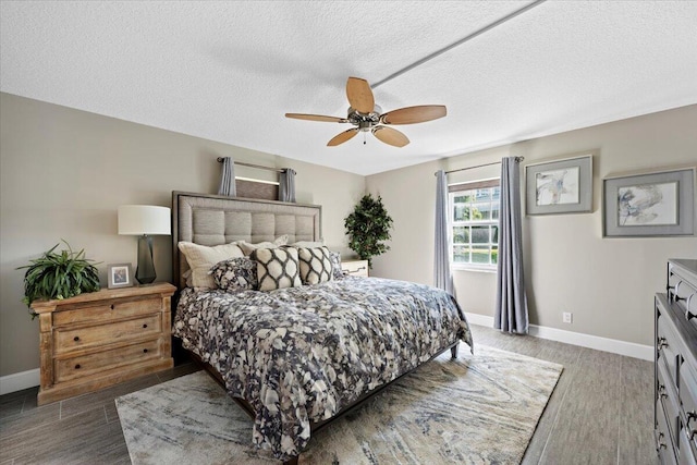 bedroom featuring baseboards, a textured ceiling, and wood finished floors