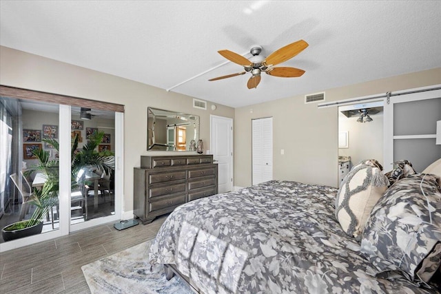 bedroom with a barn door, visible vents, and a textured ceiling