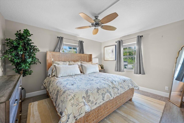 bedroom with baseboards, a textured ceiling, a ceiling fan, and light wood finished floors