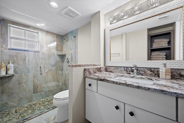 full bathroom with vanity, a shower stall, toilet, and visible vents