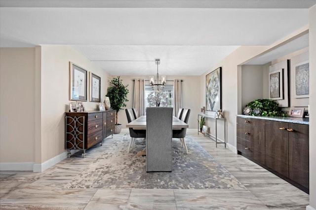 dining area featuring a chandelier and baseboards