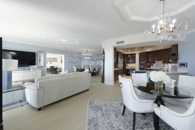 dining space with sink, ornamental molding, a chandelier, and light hardwood / wood-style floors