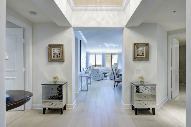 hall with light wood-type flooring and crown molding