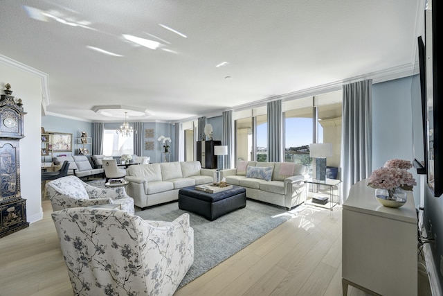 living room featuring a textured ceiling, light hardwood / wood-style floors, an inviting chandelier, and ornamental molding