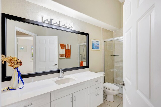 bathroom with tile patterned floors, vanity, an enclosed shower, and toilet