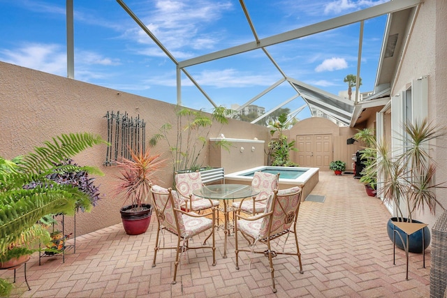 view of patio with glass enclosure and an in ground hot tub