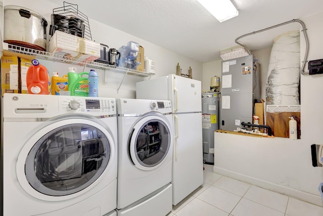 washroom featuring electric water heater, a textured ceiling, light tile patterned floors, and washing machine and clothes dryer